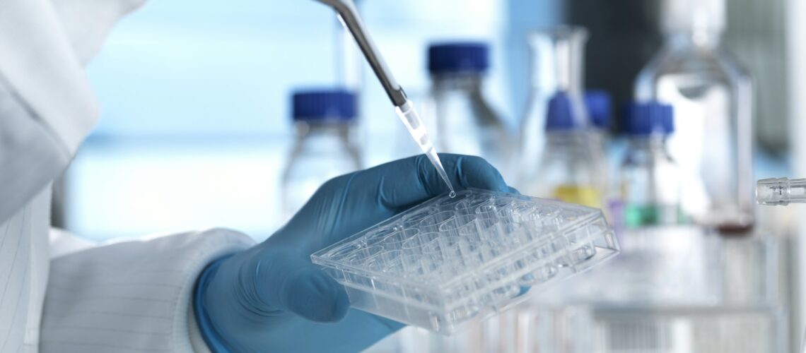 Scientist pipetting a DNA sample into a multi well plate ready for genetic testing in a laboratory